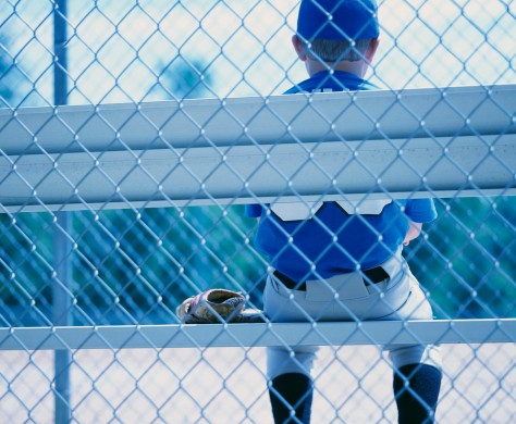 Young Baseball Player Waiting on Sidelines